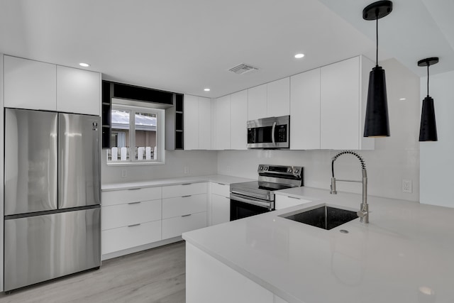 kitchen with sink, white cabinetry, stainless steel appliances, and hanging light fixtures