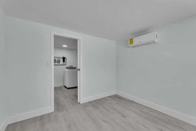 spare room with washer / dryer, light wood-type flooring, and a wall unit AC