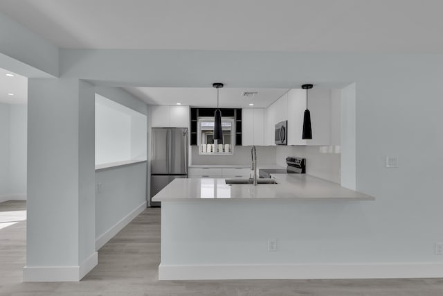 kitchen with white cabinets, sink, appliances with stainless steel finishes, decorative light fixtures, and kitchen peninsula