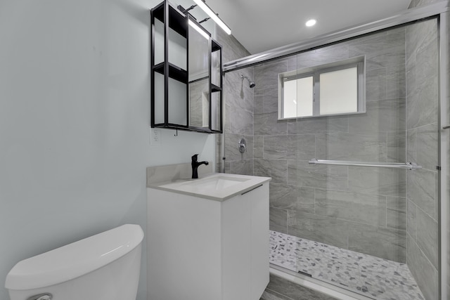 bathroom featuring vanity, toilet, and a shower with shower door