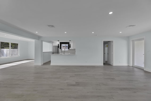 unfurnished living room featuring sink and light hardwood / wood-style flooring