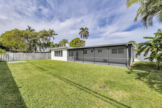 rear view of house featuring a lawn and a sunroom