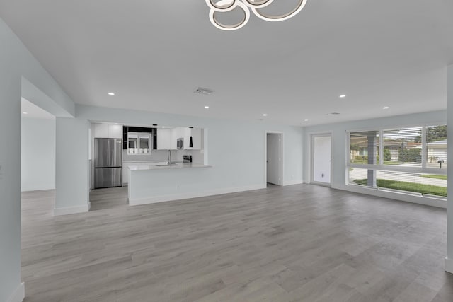 unfurnished living room with light hardwood / wood-style flooring and sink