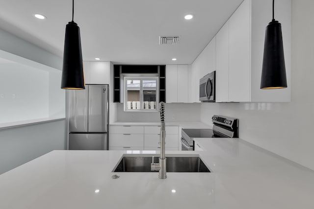 kitchen featuring sink, white cabinets, hanging light fixtures, and appliances with stainless steel finishes