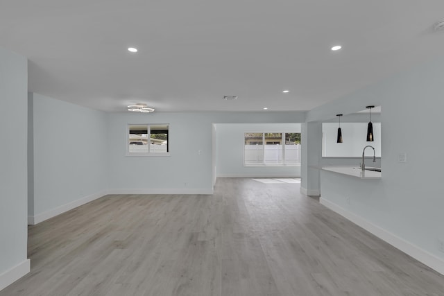 unfurnished living room featuring light wood-type flooring and sink