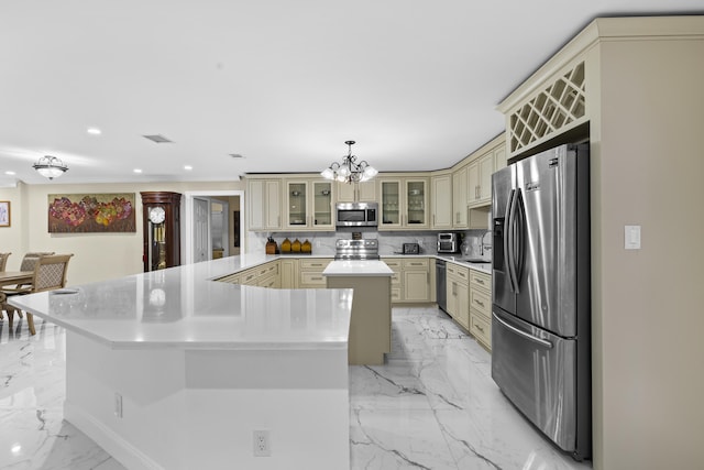 kitchen featuring stainless steel appliances, decorative light fixtures, a center island, and cream cabinets