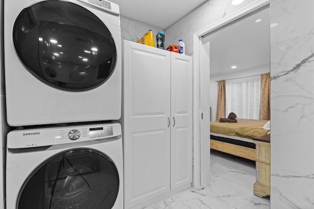 washroom featuring cabinets and stacked washer / drying machine