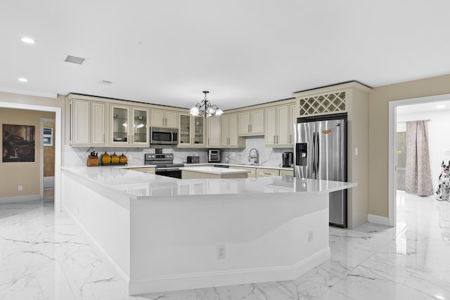 kitchen with tasteful backsplash, a center island, hanging light fixtures, stainless steel appliances, and cream cabinetry