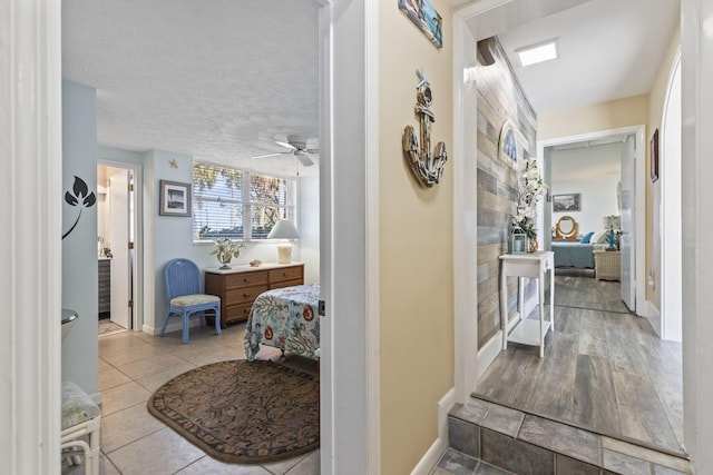 corridor featuring a textured ceiling and light tile patterned floors