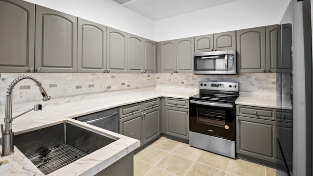 kitchen featuring sink, light tile patterned floors, gray cabinets, stainless steel appliances, and backsplash