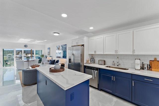 kitchen featuring stainless steel appliances, decorative backsplash, a kitchen island, white cabinets, and sink