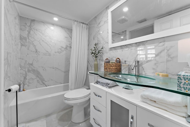 full bathroom with tile walls, toilet, vanity, and shower / tub combo