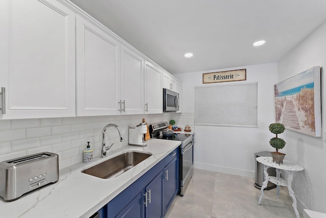 kitchen with sink, light stone countertops, blue cabinetry, stainless steel appliances, and white cabinets