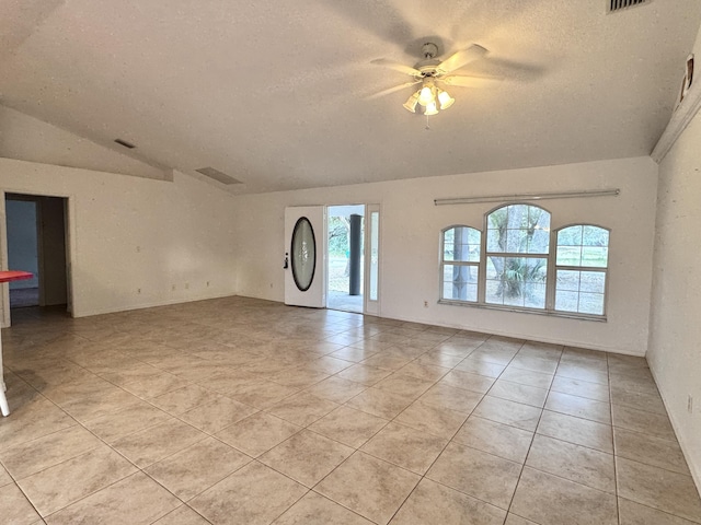 tiled empty room with ceiling fan, lofted ceiling, and a textured ceiling