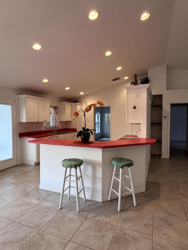 kitchen featuring a breakfast bar, white cabinetry, kitchen peninsula, and light tile patterned floors