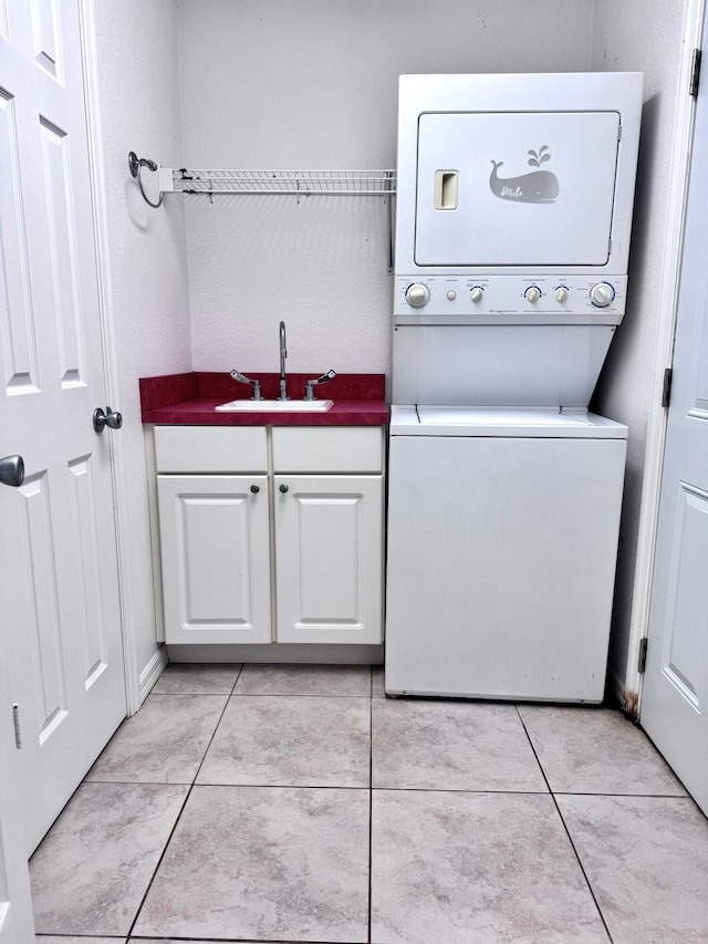 washroom with stacked washing maching and dryer, cabinets, light tile patterned floors, and sink