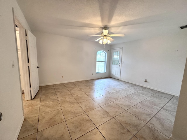 empty room with a textured ceiling, ceiling fan, and light tile patterned floors