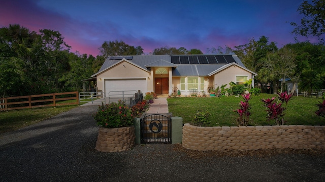 view of front of house featuring solar panels, a yard, and a garage