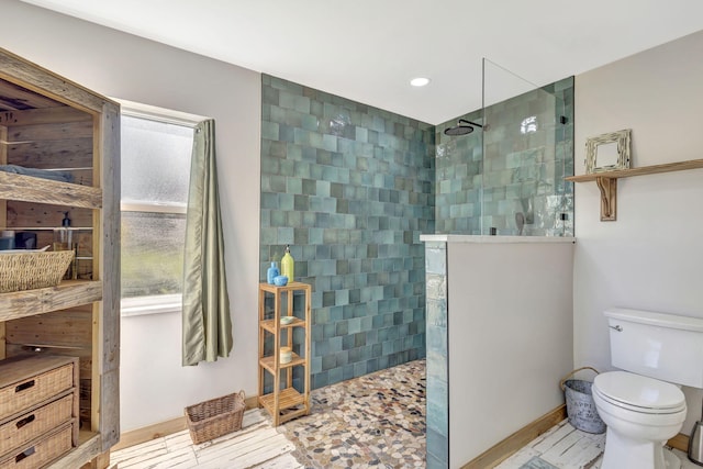 bathroom featuring a tile shower and toilet