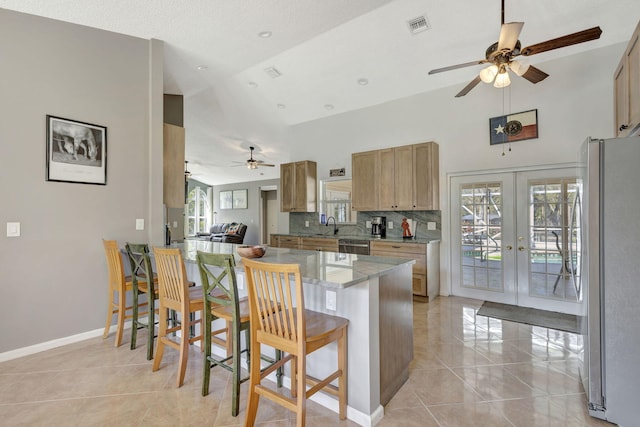 kitchen featuring kitchen peninsula, french doors, stainless steel appliances, light tile patterned floors, and a breakfast bar area