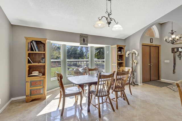 dining area featuring a textured ceiling, an inviting chandelier, and light tile patterned flooring