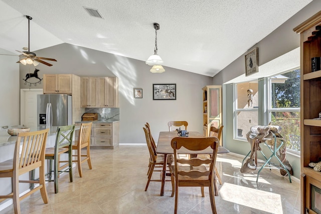 dining room with ceiling fan, lofted ceiling, and light tile patterned floors