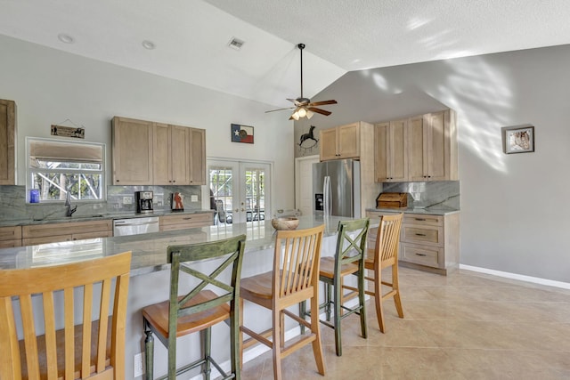 kitchen with french doors, a kitchen breakfast bar, sink, light tile patterned floors, and appliances with stainless steel finishes