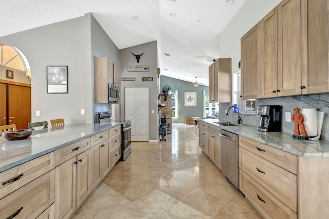 kitchen with sink, light brown cabinetry, lofted ceiling, and appliances with stainless steel finishes