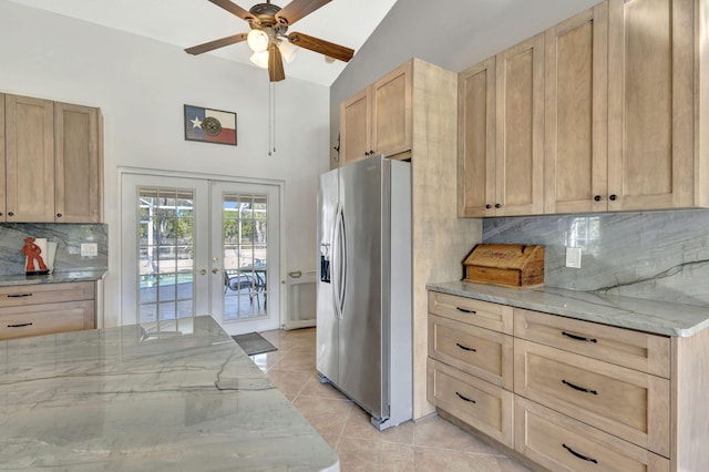 kitchen with stainless steel fridge, french doors, light brown cabinetry, light stone counters, and lofted ceiling