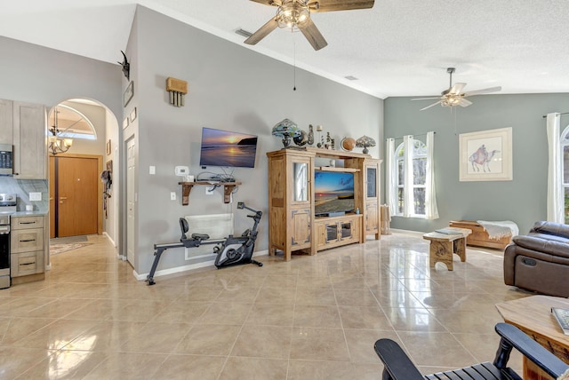 tiled living room featuring ceiling fan with notable chandelier, a textured ceiling, and vaulted ceiling