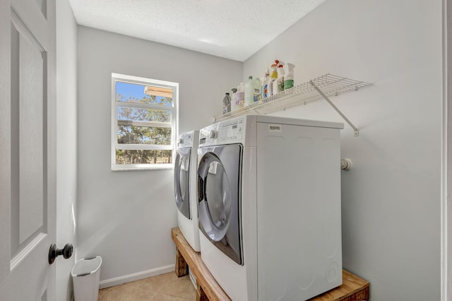 laundry room with a textured ceiling, washer and clothes dryer, and light tile patterned flooring