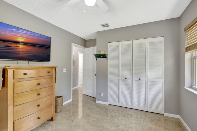 tiled bedroom with a textured ceiling, a closet, and ceiling fan