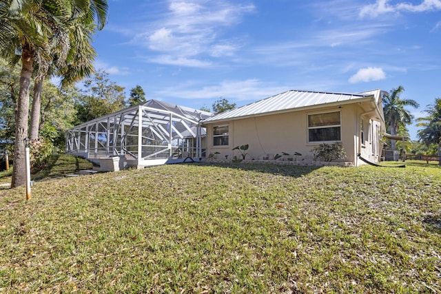 rear view of house featuring glass enclosure and a yard