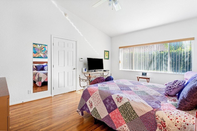 bedroom featuring ceiling fan, multiple windows, wood-type flooring, and lofted ceiling