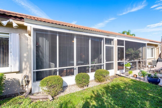 back of house with a sunroom, a patio, and a lawn