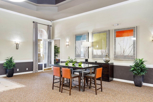 dining space featuring crown molding, light colored carpet, and a raised ceiling