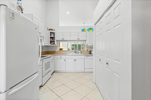 kitchen with white cabinets, white appliances, sink, and light tile patterned floors