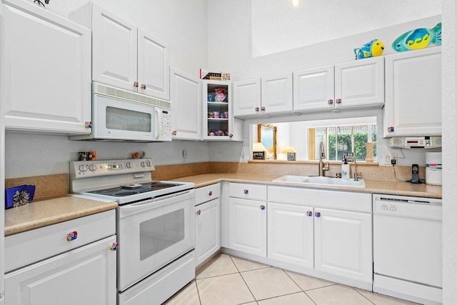 kitchen with white appliances, light tile patterned floors, sink, and white cabinets