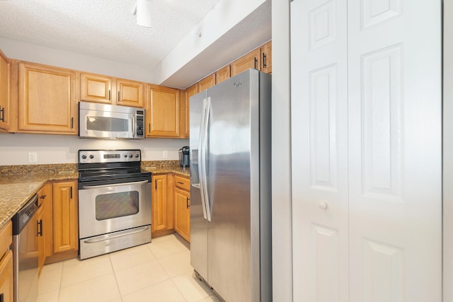 1801 N Flagler Dr Unit 840, West Palm Beach, FL 33407 - kitchen featuring stainless steel appliances, a textured ceiling, light tile patterned flooring, and stone countertops