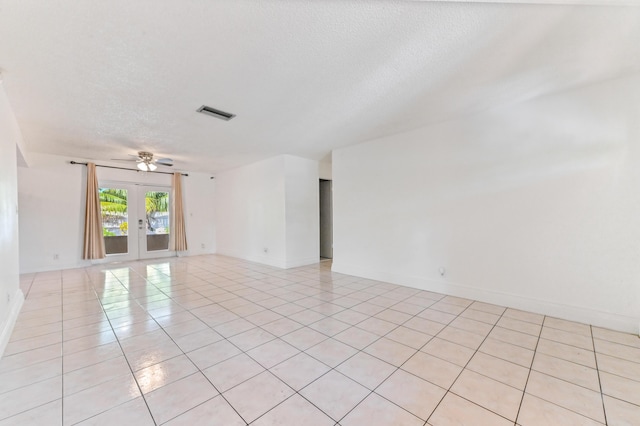 tiled empty room with ceiling fan, a textured ceiling, and french doors