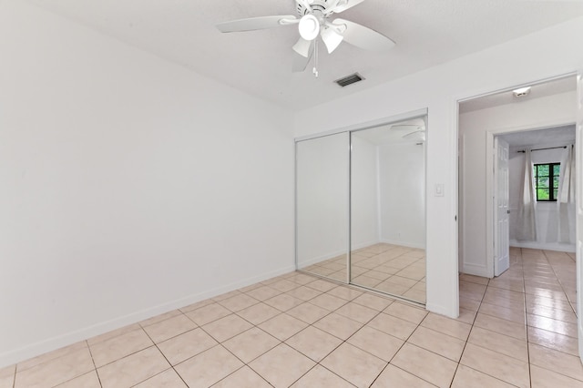 unfurnished bedroom featuring ceiling fan, a closet, and light tile patterned floors