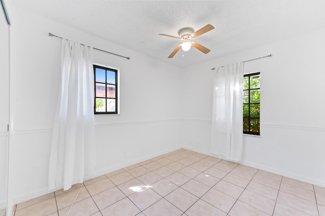 unfurnished room with ceiling fan, light tile patterned floors, and a textured ceiling