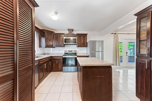 kitchen with light tile patterned flooring, french doors, a kitchen island, and stainless steel appliances