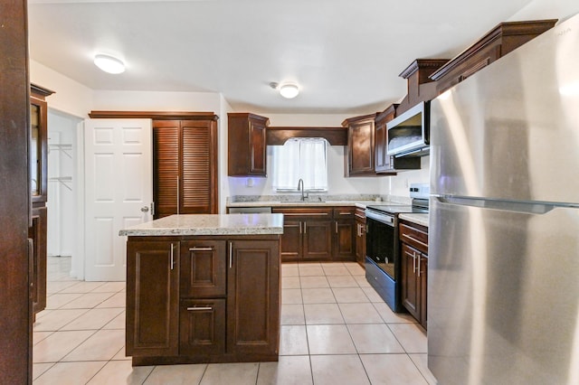 kitchen featuring a kitchen island, sink, light tile patterned floors, and stainless steel appliances