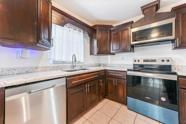 kitchen featuring light stone counters, sink, light tile patterned floors, and stainless steel appliances