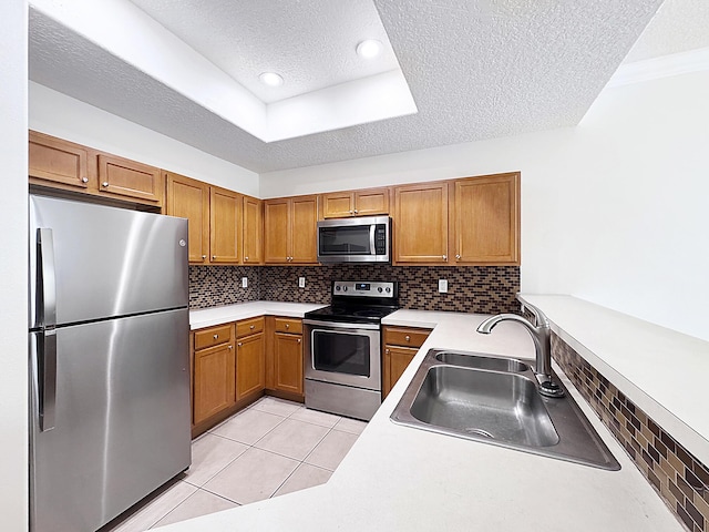 10320 SW Stephanie Way Unit 7-204, Port Saint Lucie, FL 34987 - kitchen with appliances with stainless steel finishes, a sink, a textured ceiling, brown cabinetry, and backsplash