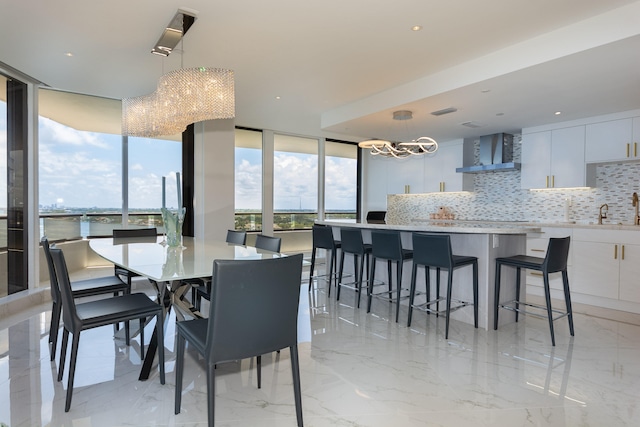 dining space featuring a water view, floor to ceiling windows, and a notable chandelier