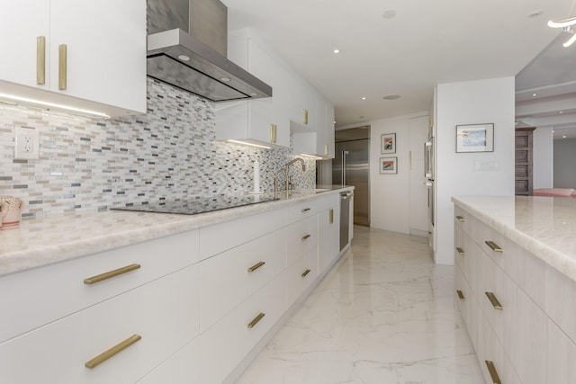 kitchen featuring white cabinetry, sink, backsplash, light stone counters, and wall chimney exhaust hood