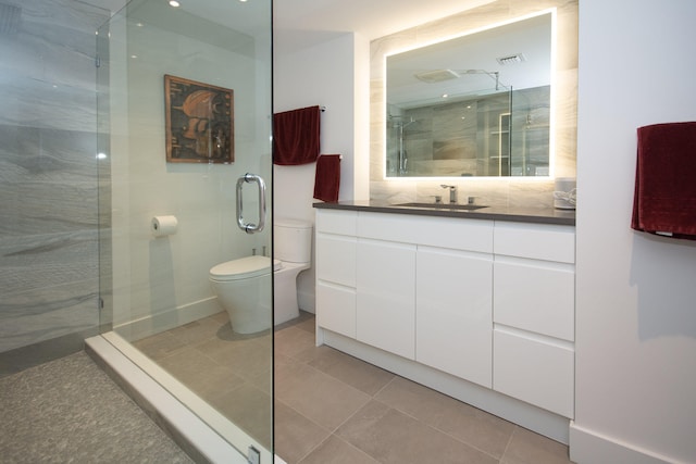 bathroom with vanity, toilet, a shower with door, and tile patterned flooring