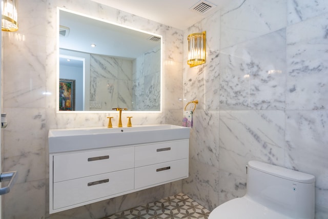 bathroom with vanity, tile walls, and toilet